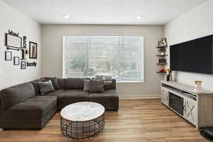 Living area with new light wood-style LVP floors and recessed lighting