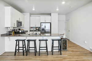 Kitchen with stainless steel appliances, a peninsula, new light wood-style LVP floors, a breakfast bar, and recessed lighting