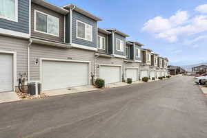 View of asphalt street and 2 car attached garage featuring a residential view