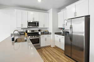 Kitchen with appliances with stainless steel finishes, new light wood-style LVP floors, and white cabinetry