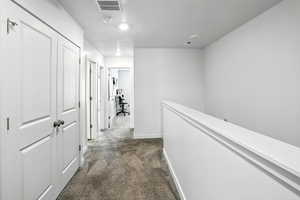 Carpeted hallway, an upstairs landing, and a textured ceiling