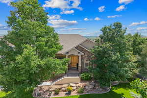 View of front of house featuring stone siding, a front lawn, a shingled roof, and stucco siding