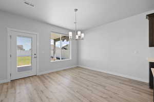 Spacious dining area with light LVP flooring and a chandelier