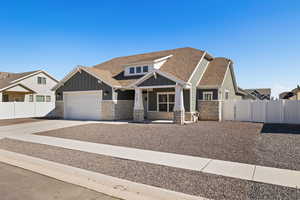 Craftsman inspired home featuring board and batten siding with stone accents, and a xeriscape front yard.