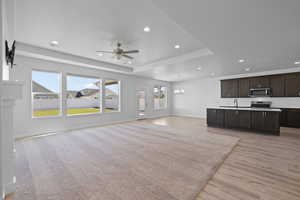 Open concept living space featuring carpeted living room, dining area, and kitchen with dark wood cabinets, and light quartz counters.