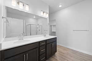 Primary bathroom with double vanity, quartz countertops, spacious shower, and soaker tub