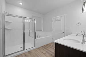 Primary bathroom with double vanity, quartz countertops, spacious shower, and soaker tub