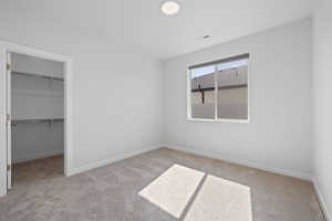 Spare bedroom with carpet and walk-in closet