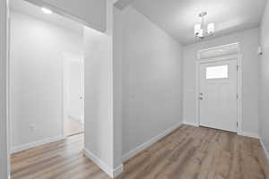 Entryway featuring light LVP floors and a chandelier