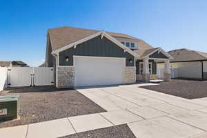 Craftsman inspired home featuring board and batten siding with stone accents, and a xeriscape front yard.