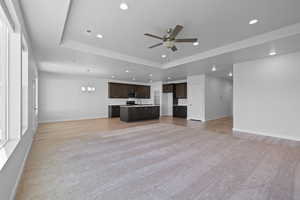 Open concept living space featuring carpeted living room, dining area, and kitchen with dark wood cabinets, and light quartz counters.