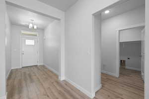 Foyer with light wood-style flooring and a chandelier