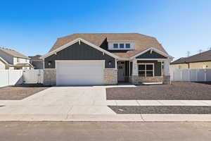 Craftsman inspired home featuring board and batten siding with stone accents, and a xeriscape front yard.