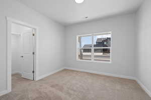 Spare bedroom with carpet and walk-in closet