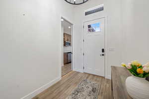 Entryway with light wood finished floors, a high ceiling, and a chandelier