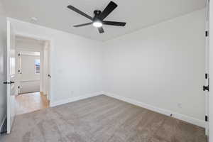 Carpeted spare room featuring ceiling fan and baseboards
