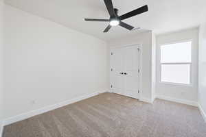Unfurnished bedroom with carpet, ceiling fan, and a closet