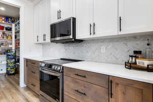 Kitchen with stainless steel appliances, white cabinets, and light wood finished floors