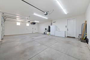 Garage with a garage door opener, white refrigerator, and freestanding refrigerator