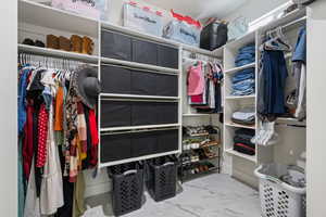Spacious closet featuring marble finish flooring