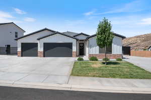 Modern farmhouse featuring an attached garage, driveway, board and batten siding, brick siding, and a tiled roof