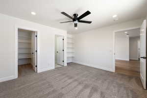 Unfurnished bedroom featuring a walk in closet, carpet flooring, recessed lighting, and a ceiling fan