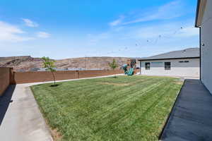 Fenced backyard with a playground and a mountain view