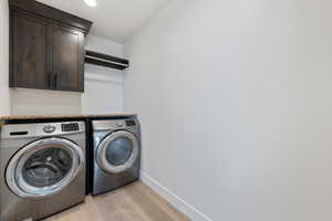 Laundry area featuring washer and dryer, cabinet space, light wood-style flooring, and recessed lighting