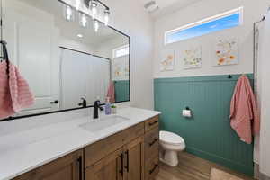 Full bathroom with vanity, wood finished floors, a wainscoted wall, and curtained shower