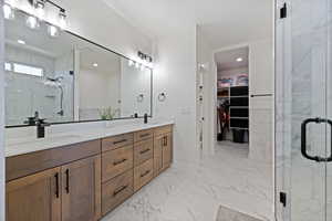 Full bathroom with double vanity, a marble finish shower, marble finish flooring, a walk in closet, and recessed lighting