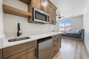 Kitchen featuring stainless steel appliances, open shelves, a ceiling fan, light wood-style floors, and light countertops