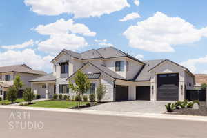 View of front of home featuring a garage, stone siding, decorative driveway, a tiled roof, and board and batten siding