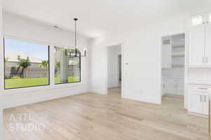 Unfurnished dining area featuring a chandelier and light wood finished floors