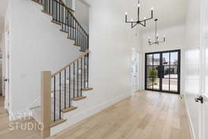 Foyer entrance featuring a chandelier, a high ceiling, wood finished floors, and stairway