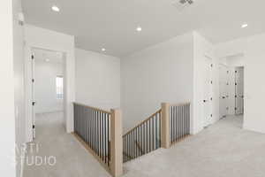 Hallway with an upstairs landing, light carpet, and recessed lighting