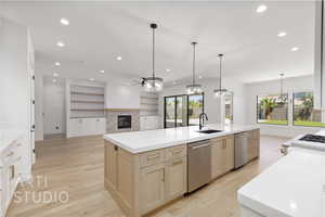 Kitchen with stainless steel dishwasher, a glass covered fireplace, a kitchen island with sink, recessed lighting, and light wood-style flooring