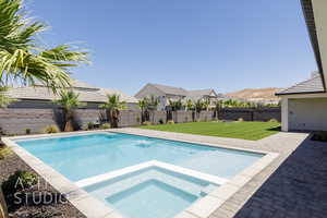 View of pool featuring a fenced backyard, a pool with connected hot tub, and a patio