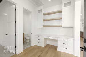 Unfurnished office with built in study area, light wood-style floors, and recessed lighting