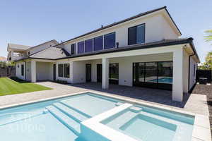 Back of house with stucco siding, a pool with connected hot tub, and a patio