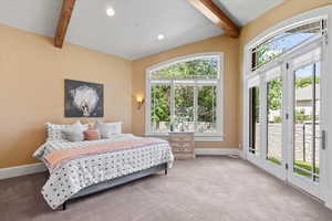 Carpeted bedroom featuring beamed ceiling and access to exterior