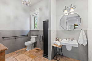 Bathroom featuring tile walls, wainscoting, and a chandelier