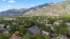 Aerial view of property and surrounding area featuring a mountainous background and nearby suburban area