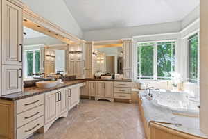 Bathroom featuring vanity, lofted ceiling, and a jetted tub