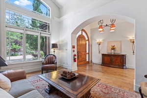 Living room with arched walkways, plenty of natural light, wood-type flooring, and a towering ceiling