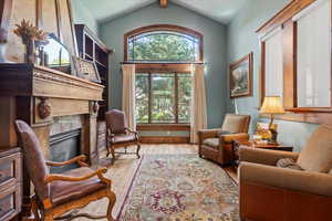 Sitting room with hardwood / wood-style floors, vaulted ceiling, and a high end fireplace