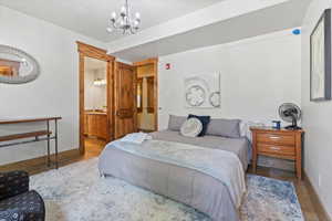 Bedroom with a chandelier, wood finished floors, and ensuite bathroom