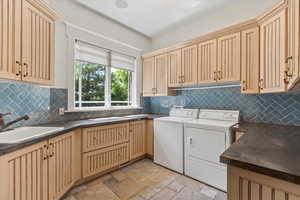 Laundry room with cabinet space, washing machine and dryer, and stone tile floors