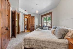 Bedroom with light carpet, a wainscoted wall, and a decorative wall