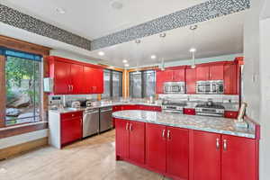 Kitchen with red cabinetry, appliances with stainless steel finishes, stainless steel counters, recessed lighting, and tasteful backsplash