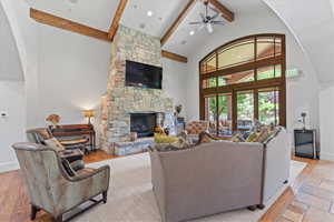 Living room with beam ceiling, high vaulted ceiling, a ceiling fan, and a fireplace
